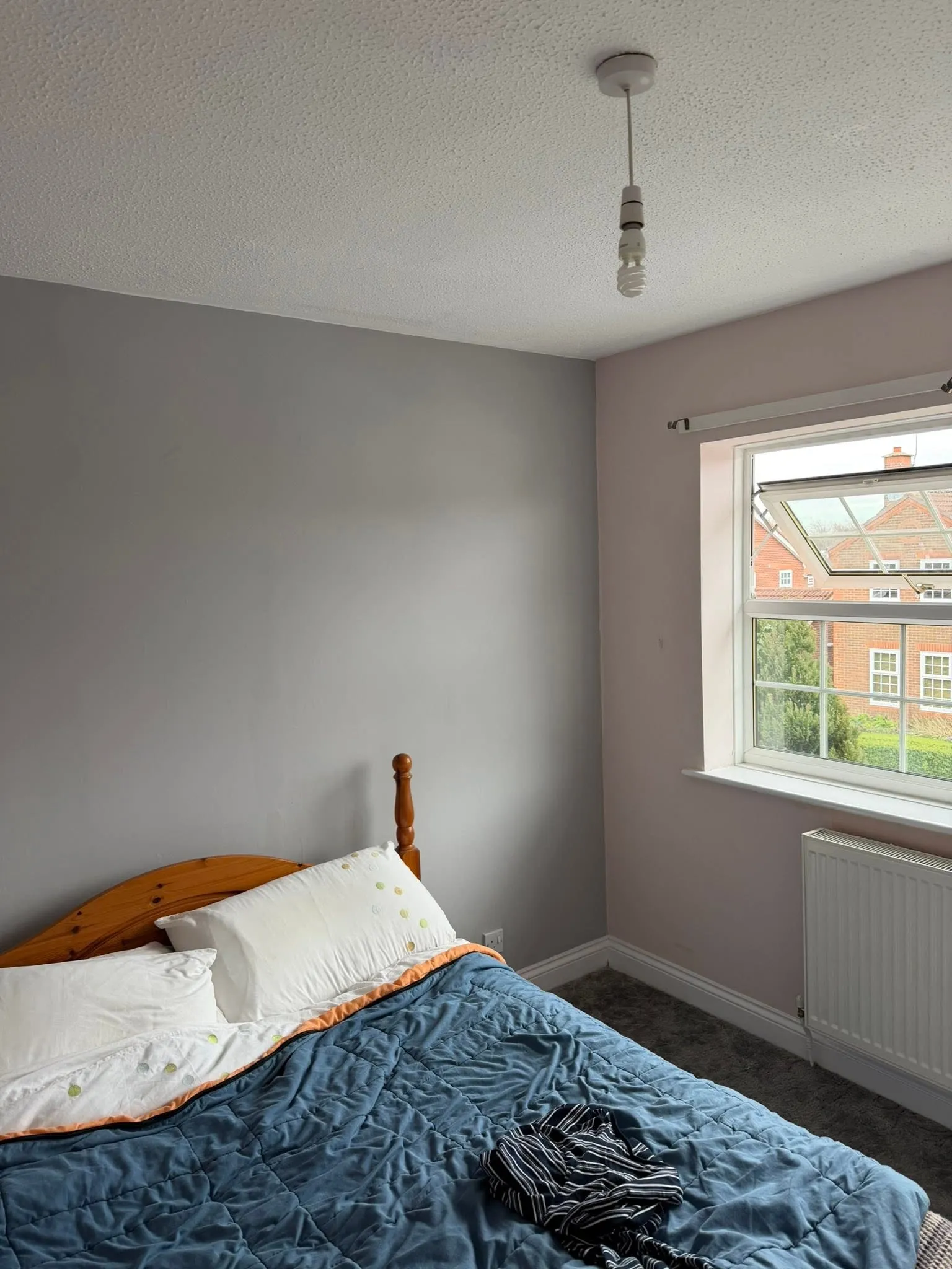 Bedroom with newly painted soft grey walls, white window frame and a wooden bed