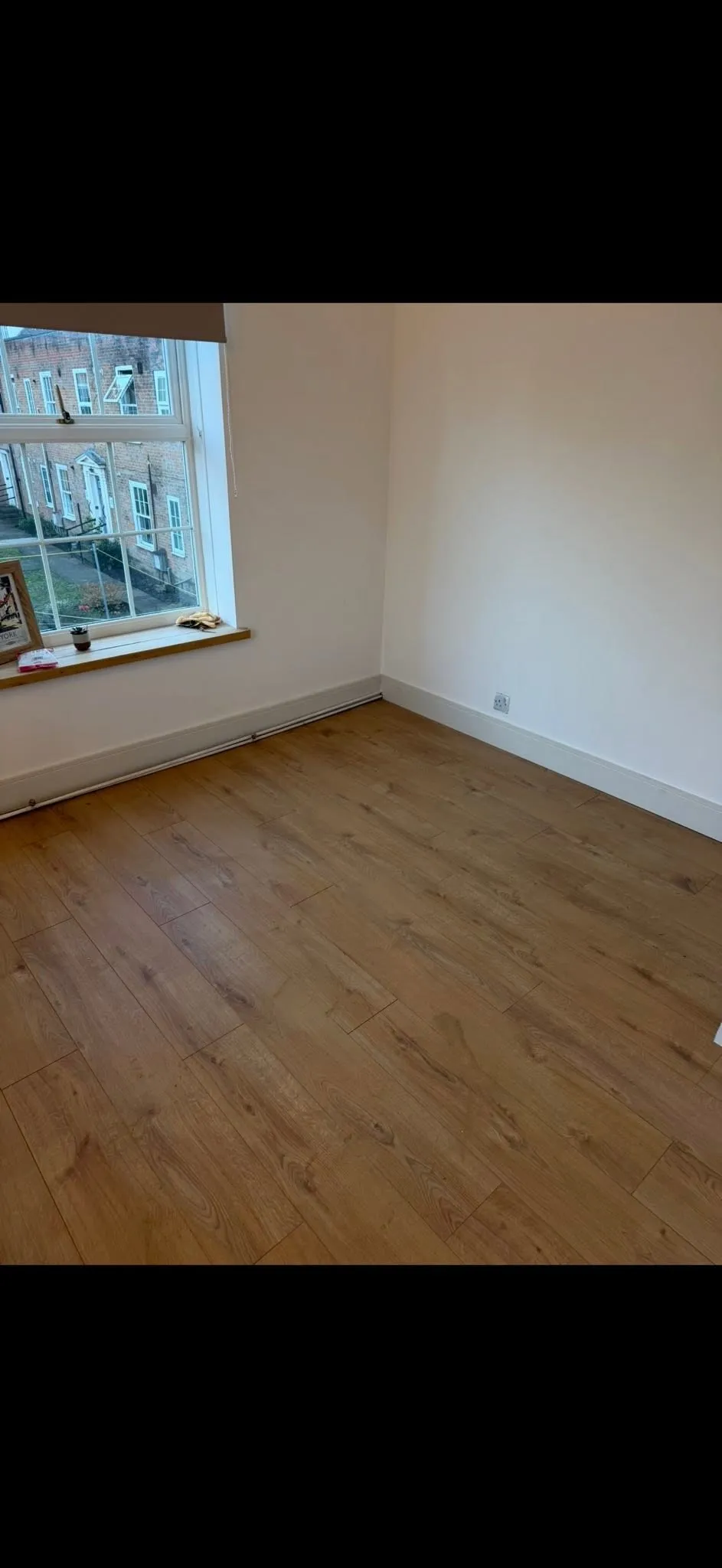 The same room with new light oak laminate flooring laid throughout