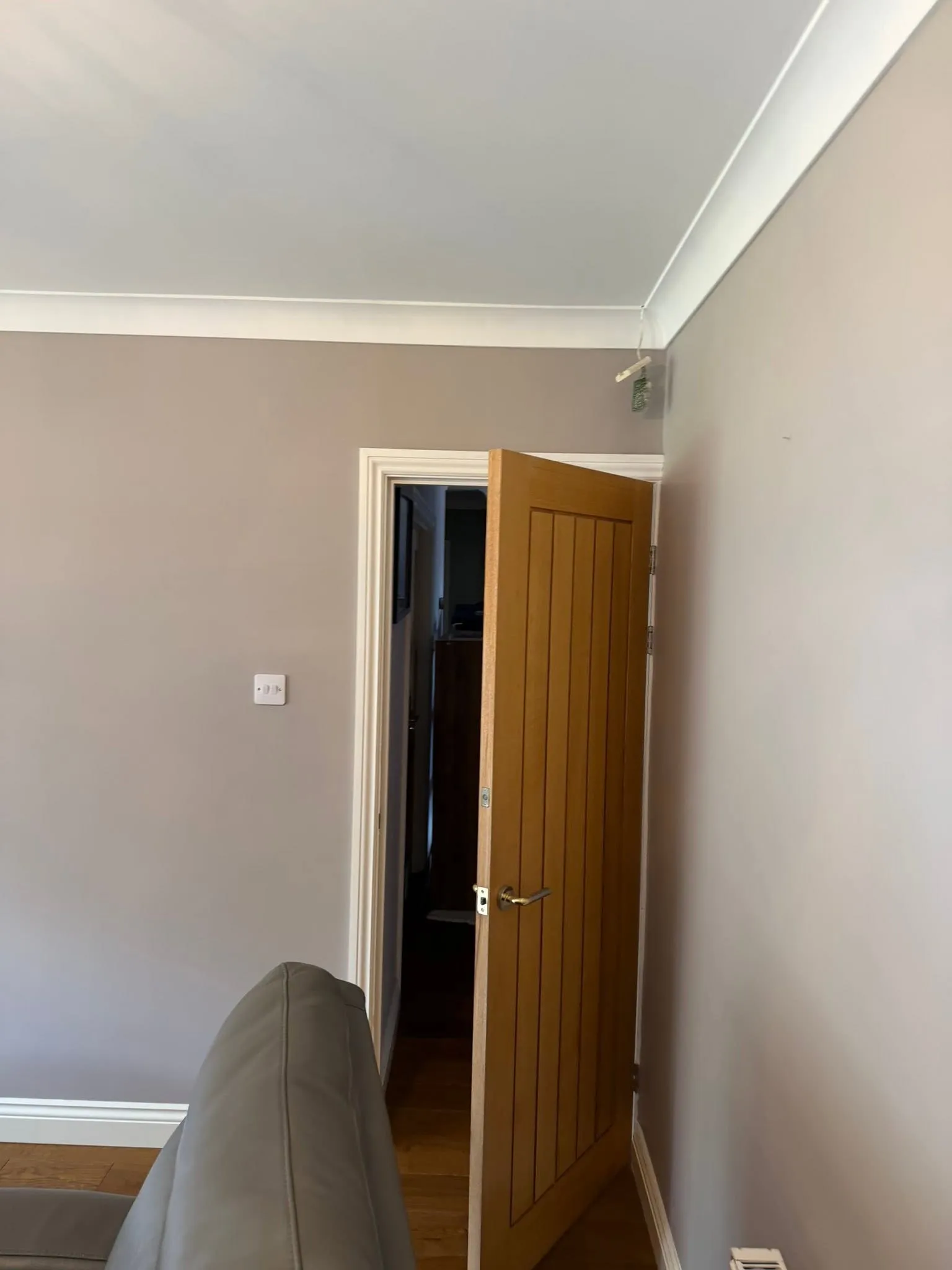 Freshly painted room in warm grey with a solid oak door and white trim