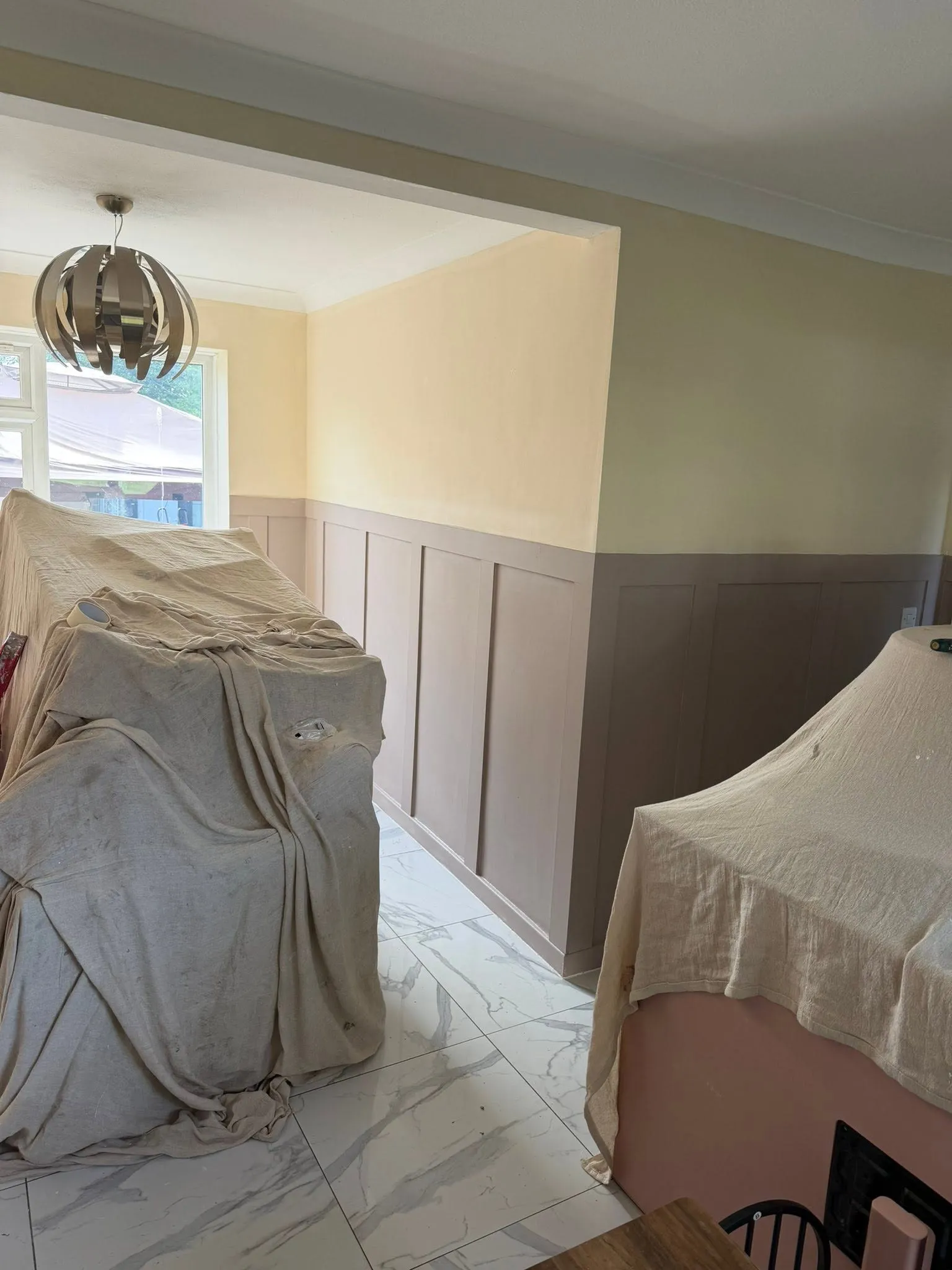 Dining room part-way through decorating with furniture covered by dust sheets